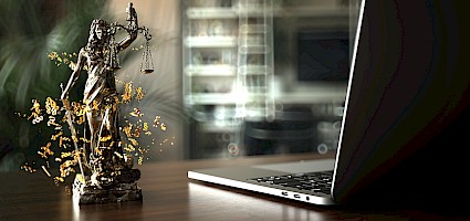 Laptop und Justizia-Figur als Sinnbild für das Vergaberecht