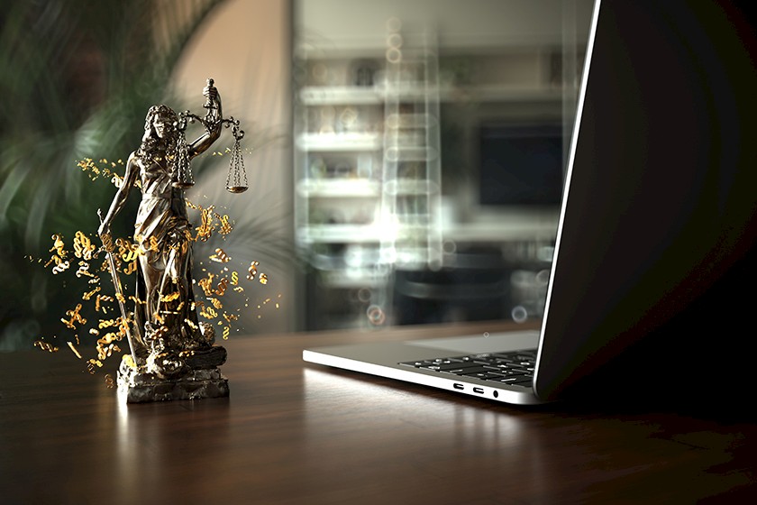 Laptop und Justizia-Figur als Sinnbild für das Vergaberecht