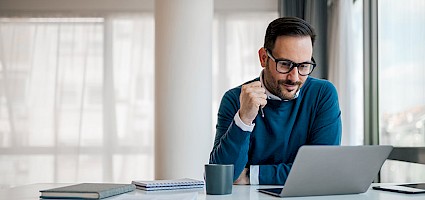 Bieterfragen stellen: Person sitzt vor Laptop