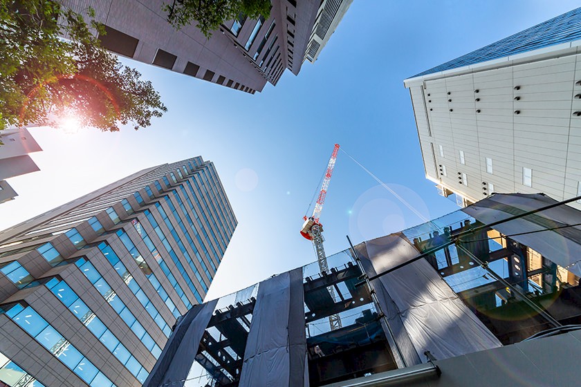 Bauwirtschaft in Österreich: Hochhäuser von unten bei blauem Himmel