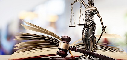 Justitia Statue mit Richterhammer und Buch auf einem Tisch